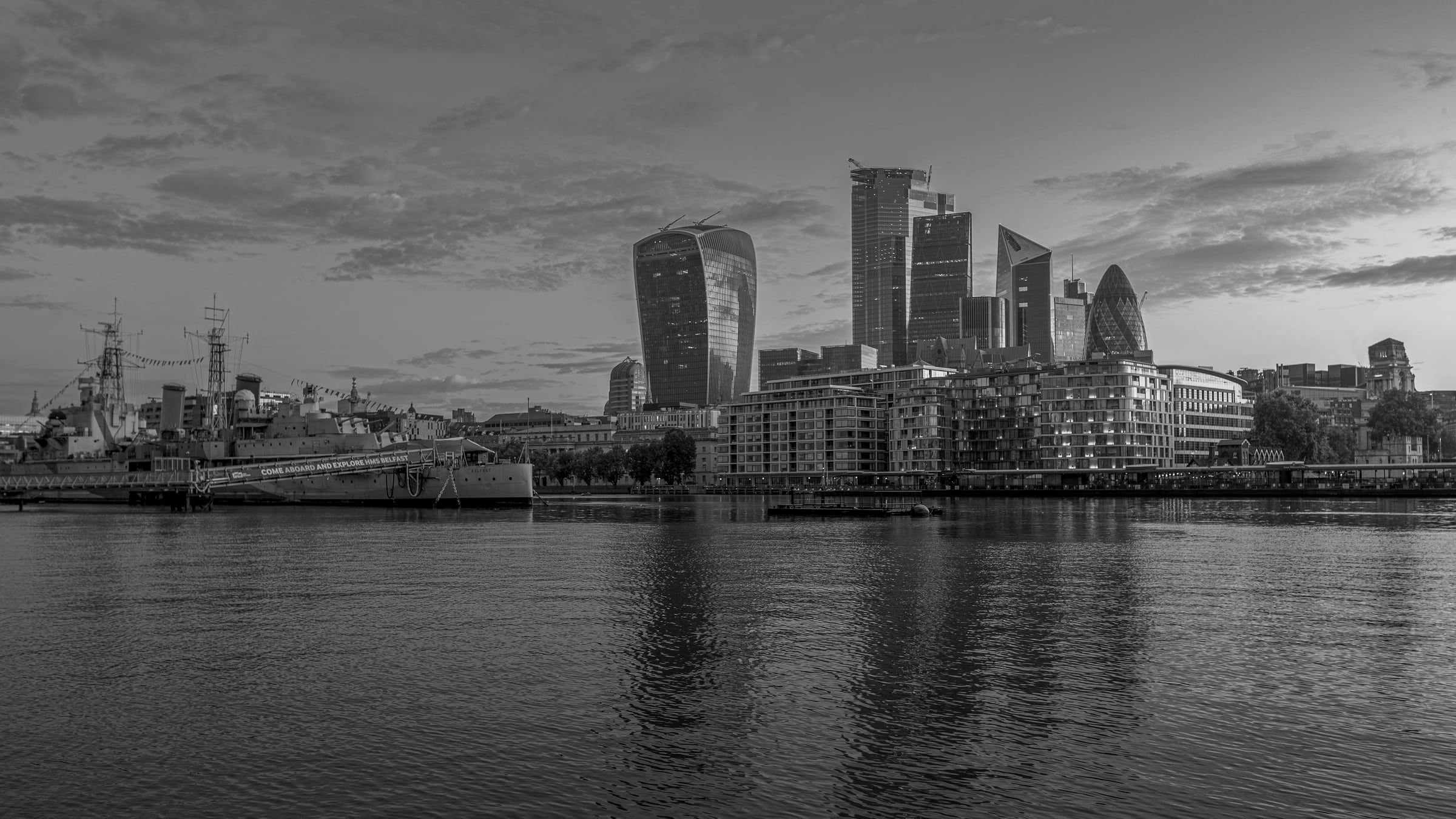 The City of London skyline across the Thames at golden hour.